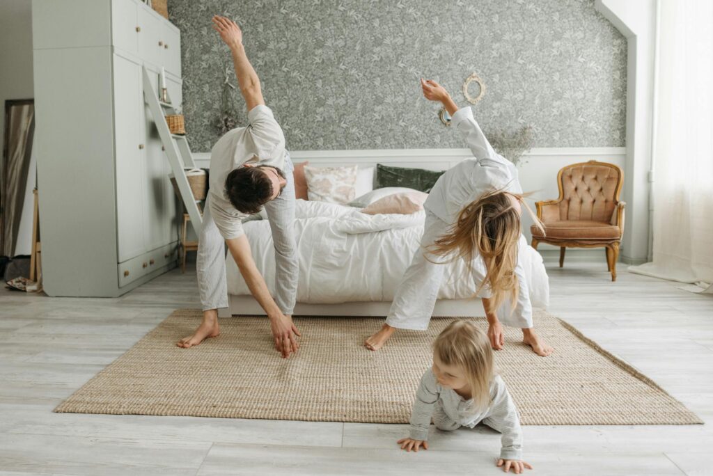 A family stretches together in a cozy bedroom, enjoying morning activities.